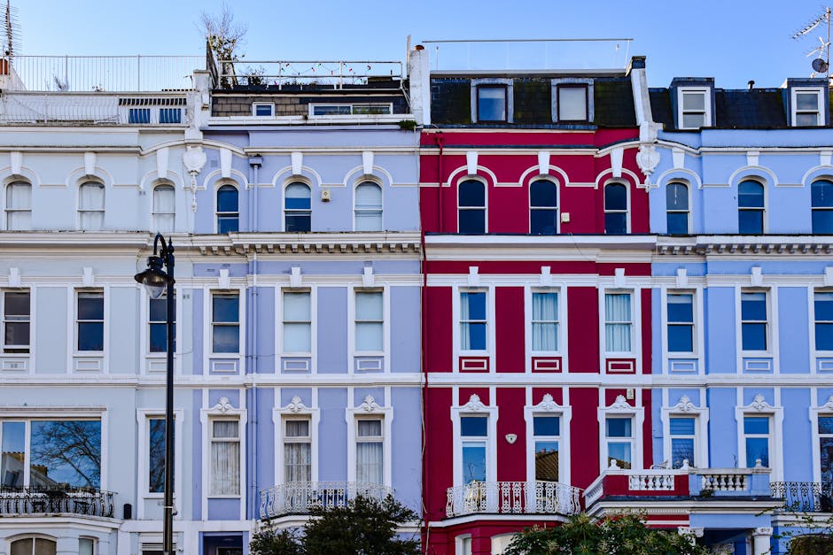 View of a row of Victorian terraced houses on Hampton Hill High Street, illuminated by warm sunlight during late afternoon or early evening. The buildings feature brick facades, some with decorative w